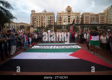 Malaga, Espagne. 13 octobre 2023. Des manifestants tiennent des drapeaux palestiniens derrière eux alors qu'ils participent à une manifestation de solidarité avec la Palestine sur la place Plaza de la Marina, au milieu du conflit entre Israël et la Palestine. Des dizaines de personnes ont participé à une manifestation pour condamner la violence contre le peuple palestinien et exiger la fin de l'apartheid israélien. La guerre israélo-palestinienne, qui a suivi l'attaque massive du Hamas contre Israël, a entraîné la mort de milliers de personnes et le blocus total de la bande de Gaza. Crédit : SOPA Images Limited/Alamy Live News Banque D'Images