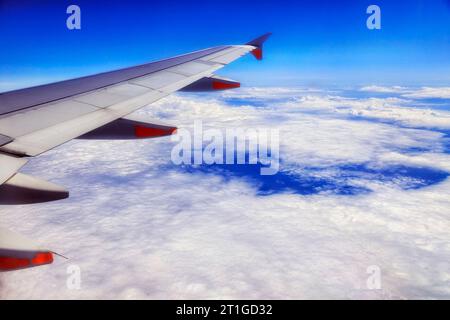 Aile d'avion de passagers avec des moteurs volant au-dessus du paysage nuageux de l'océan Pacifique vers la Nouvelle-Zélande. Banque D'Images