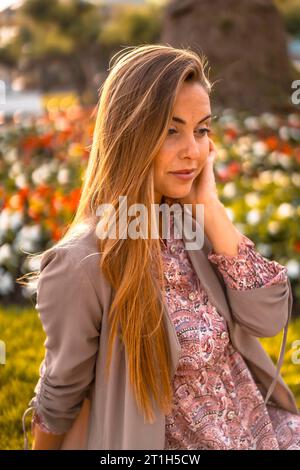 Lifestyle, un jeune entrepreneur. Caucasien et blonde avec imperméable marron et robe fleurie dans la ville. Vue aérienne à côté de fleurs dans une belle Banque D'Images