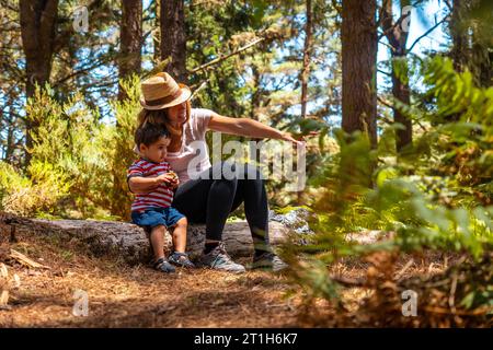 Portrait d'une mère avec son fils assis sur un arbre dans la nature à côté des pins, Madère. Portugal Banque D'Images