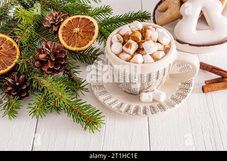 Belle tasse avec motif tricoté du nouvel an avec du cacao chaud ou une boisson au chocolat avec des guimauves sur une table en bois blanc. Concept de Noël confortable Banque D'Images