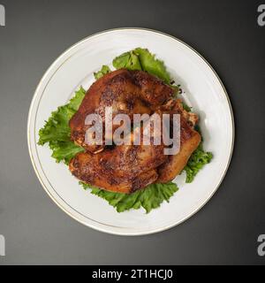 Cuisses de porc grillées avec de la laitue sur une plaque blanche vue de dessus Banque D'Images