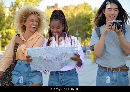 Trois amis multiraciaux en visite guidée avec une carte locale et une caméra à Madrid, en Espagne. Banque D'Images