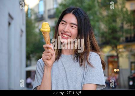 Jeune homme taïwanais souriant avec une glace à la mangue en été. Banque D'Images