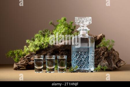 Gin bleu en carafe sur un fond de vieux accrocs et de branches de genévrier avec des baies. Fond beige avec espace de copie. Banque D'Images