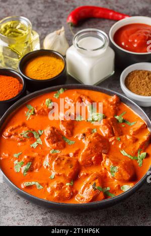 Poulet tikka masala est un plat composé de morceaux de poulet marinés rôtis dans une sauce crémeuse épicée en gros plan sur l'assiette sur la table. Vertical Banque D'Images