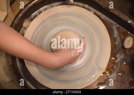 Potter girl travaille sur la roue de potier, faisant pot en céramique à partir d'argile dans l'atelier de poterie. Art et concept de passe-temps Banque D'Images