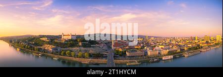 Vue panoramique sur le coucher du soleil de Bratislava, Slovaquie, avec le Danube, le château de Bratislava, la ligne d'horizon moderne et les ponts dans la lumière dorée chaude du soir Banque D'Images