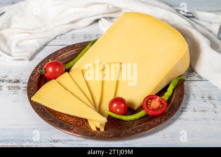 Fromage vieilli sur une plaque de cuivre. Cheddar de vache frais biologique sur fond de bois Banque D'Images