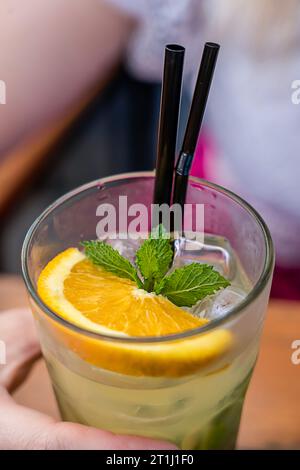 Un cocktail cool dans les mains d'une femme. Cocktails multicolores avec glaçons. Liquide rafraîchissant frais. Banque D'Images