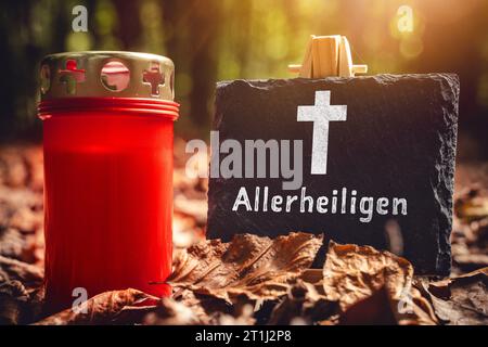 Augsbourg, Bavière, Allemagne. 13 octobre 2023. Vacances de la Toussaint, Une bougie tombante dans la forêt avec une plaque avec texte : All Saints Day PHOTO MONTAGE *** Allerheiligen Feiertag, Eine Grabkerze im Wald mit einer Tafel mit texte : Allerheiligen FOTOMONTAGE crédit : Imago/Alamy Live News Banque D'Images