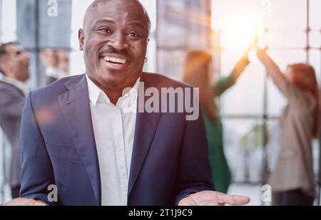 un jeune homme d'affaires africain lève la paume de sa main contre l'arrière-plan de ses collègues Banque D'Images