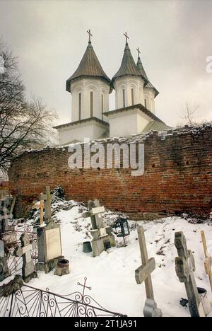 Tutana, comté d'Arges, Roumanie, 2000. Vue extérieure de St. Église Athanase au monastère de Tutana, monument historique du 15e siècle. Cimetière et ruines des murs défensifs. Banque D'Images