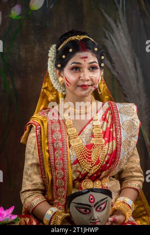 Portrait de la belle fille indienne de Durga Idol Agomoni concept photo intérieure portant sarée indienne traditionnelle, bijoux en or et bracelets. Maa Durga Banque D'Images