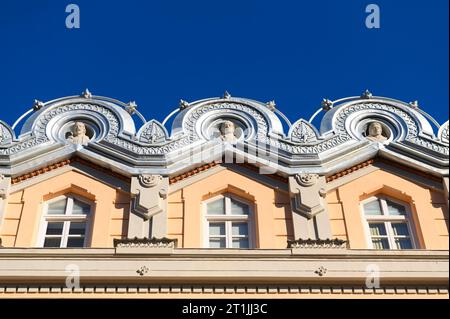 Trois sculptures décorant la partie supérieure de la structure. Élément architectural dans la façade ou le mur extérieur du Théâtre Romea. Banque D'Images