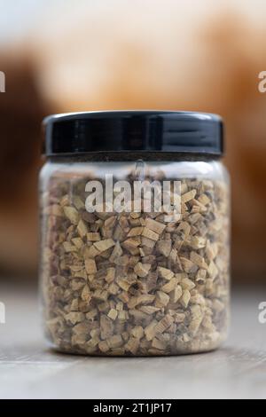 Portrait d'un pot en plastique ou d'un pot plein de morceaux de réglisse frais et séchés de glycyrrhiza glabra pour préparer une tasse de thé frais. Les herbes sont prêtes à être utilisées i Banque D'Images