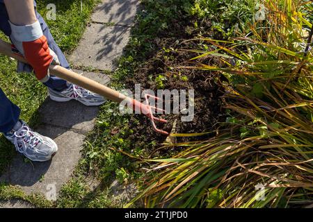 Un enfant creuse un lit dans le jardin avec une fourche Banque D'Images