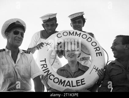 Gracie Fields pose avec un groupe de marins dans le port de Trincomalee, à Ceylan, au cours d'une visite à la flotte des Indes britanniques, 20 octobre 1945. Des artistes de guerre : music hall star Gracie Fields et un groupe de marins posent avec un sauveteur de la Commodore's Barge dans port de Trincomalee, à Ceylan au cours d'une visite à la flotte des Indes britanniques. Banque D'Images