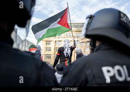 14 octobre 2023, Hesse, Francfort-sur-le-main : un participant à une manifestation pro-palestinienne agite un drapeau palestinien pendant que des policiers observent la situation. Photo : Hannes P. Albert/dpa Banque D'Images