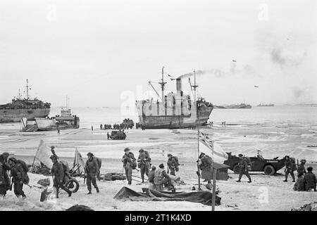 Troupes à terre sur l'une des plages de Normandie, passé le pavillon blanc de la marine une partie de plage, 7 juin 1944. D-Day, le 6 juin 1944 : le pavillon blanc de la Marine parti une plage sur la côte normande que les troupes britanniques vers l'intérieur des terres à partir de la sec, les engins de débarquement. Banque D'Images