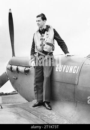 Officier pilote H. A. Picard n° 350 de l'Escadron (belge), sur l'aile de son Spitfire, à Kenley, juillet 1942. En novembre 1941, le premier escadron de volontaires belges a été formé en chasse. L'un de ses pilotes a été officier pilote H. A. Picard, qu'on voit ici sur l'aile de son Spitfire, à Kenley en juillet 1942. Son appareil était parmi un nombre 'présenté' par le Congo belge, et porte le nom d'une de ses principales villes. Banque D'Images