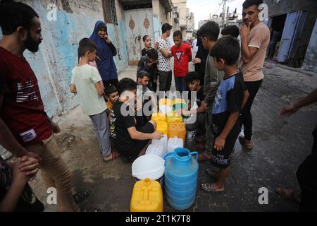 Rafah, Gaza. 14 octobre 2023. Des Palestiniens font la queue pour faire le plein d’eau dans le camp de réfugiés de Rafah, dans le Sud de la bande de Gaza, samedi 14 octobre 2023. Les groupes d’aide internationaux et les grandes puissances ont plaidé auprès d’Israël pour qu’il établisse des zones de sécurité à Gaza où des milliers de personnes ont lutté le 14 octobre pour sortir d’une grande partie du territoire palestinien sous la menace d’attaques. Photo par Ismael Mohamad/UPI crédit : UPI/Alamy Live News Banque D'Images