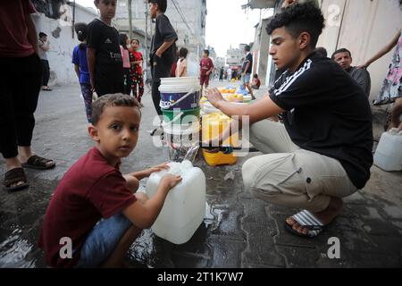 Rafah, Gaza. 14 octobre 2023. Des Palestiniens font la queue pour faire le plein d’eau dans le camp de réfugiés de Rafah, dans le Sud de la bande de Gaza, samedi 14 octobre 2023. Les groupes d’aide internationaux et les grandes puissances ont plaidé auprès d’Israël pour qu’il établisse des zones de sécurité à Gaza où des milliers de personnes ont lutté le 14 octobre pour sortir d’une grande partie du territoire palestinien sous la menace d’attaques. Photo par Ismael Mohamad/UPI crédit : UPI/Alamy Live News Banque D'Images