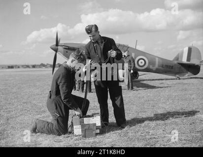 Collection officielle du Ministère de l'air de la Seconde Guerre mondiale des armuriers préparent des ceintures de munitions de 303 pouces pour le Hawker Hurricane Mk I DU-J (série L1926) de l'escadron no 312 (Tchèque) RAF. Piloté par Alois Vašátko, il partage la fusillade d'un Junkers Ju 88 le 8th octobre 1940. Banque D'Images