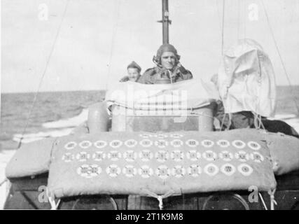 Opérations de la Royal Air Force à Malte, Gibraltar et la Méditerranée, 1940-1945. Le Flight Lieutenant E G :, maître de la haute vitesse HSL 107 Lancement de l'unité de secours en mer, de Malte, est assis sur la tourelle siège dans la timonerie comme il dirige le navire dans la Méditerranée à l'ouest de l'île pour sauver un pilote abattu. Derrière lui est l'un des membres de son équipage, l'Aviateur-chef S Ibister. Les ceintures de miniatures peintes sur la toile devant indiquer le nombre de pick-ups à ce jour. Banque D'Images