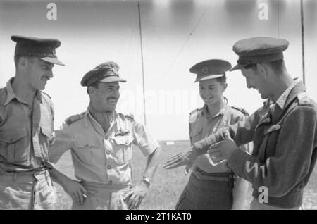 Opérations de la Royal Air Force au Moyen-Orient et en Afrique du Nord, 1939-1943. Les pilotes d'Afrique du Sud au Nord de Kairouan, Tunisie, Temmar/raconter les événements du 22 avril 1943, lorsque Curtiss Kittyhawk de no 7, Aile sud-africain et Supermarine Spitfire du 1er Escadron SAAF, intercepté et abattu une grande formation de Messerschmitt Me 323 avions de transport et leurs chasseurs d'escorte, qui s'efforce de renforcer les forces de l'axe en Afrique du Nord, au large du Cap Bon, Tunisie. Ils sont, (de gauche à droite) : Major J D'W (Sweep chef de l'Escadre n° 7), le Major J E Parsonson (Commandant Banque D'Images