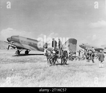 Royal Air Force- l'Italie, les Balkans et le sud-est de l'Europe, 1942-1945. Dakota Douglas Mark III du No 267 Squadron RAF le déchargement des fournitures pour les forces alliées à Araxos, Grèce, tout en étant l'objet de beaucoup d'intérêt parmi les paysans locaux. Banque D'Images