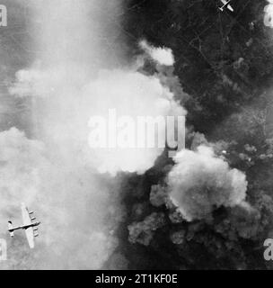 Royal Air Force Bomber Command, 1942-1945. L'Avro Lancaster (en bas à gauche) et d'un Handley Page Halifax (en haut à droite) voler plus de Essen, en Allemagne, au cours d'une grande attaque de jour par 771 avions qui a infligé de graves dégâts sur les bâtiments et les autres industries. Le Lancaster est en survolant l'aciérie Krupp à partir de laquelle les nuages de fumée à l'explosion des bombes est à la hausse dans l'air. Banque D'Images