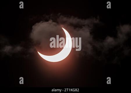 Dans cette image prise avec un filtre solaire, la lune et le soleil jettent un coup d'œil à travers les nuages pendant l'éclipse solaire annulaire de samedi matin, vue depuis San Jose, en Californie, qui a vu 75% du soleil obscurci. C'était la dernière éclipse de 2023. 14 octobre 2023 (crédit photo : David Elkins/Alamy Live News) Banque D'Images