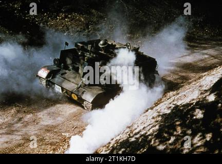 Les transporteurs en service universel avec l'armée britannique pendant la Seconde Guerre mondiale une mitrailleuse légère Bren carrier faire son chemin à travers la fumée vers le bas une route de terre. Banque D'Images