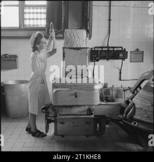 Une boulangerie moderne- le travail de l'Émerveillement Boulangerie, Wood Green, Londres, Angleterre, RU, 1944 à l'Étonnant Bakery à Wood Green, un travailleur régule le débit de pâte, qui descend de l'étage supérieur, dans la division automatique et d'un poids de la machine. Banque D'Images