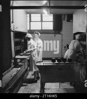 Une boulangerie moderne- le travail de l'Émerveillement Boulangerie, Wood Green, Londres, Angleterre, RU, 1944 travailleurs de l'Étonnant Boulangerie, Wood Green, placez des morceaux de pâte en fermentation pour boîtes automatiques dans la cuve finale. Comme il s'agit d'une boulangerie mécanisée, selon la légende originale, 'c'est une des rares fois que la pâte est touché à la main'. Banque D'Images