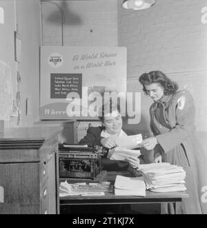 Fête de Noël pour le Cavalier Devereux's Daughter- Noël en temps de guerre, Pinner, Middlesex, décembre 1944 Mme E Renshaw (à droite) reçoit le cavalier Devereux a demande de cadeau à l'administration centrale du YMCA, et prépare pour faire part de l'acheter en son nom. Trooper Devereux a demandé qu'un arbre de Noël pour sa femme et sa fille être achetés par l'entremise de "dons" de la Ligue d'accueil. Banque D'Images