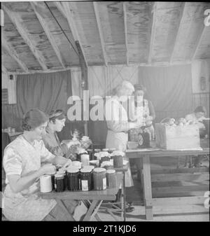 Le jardinage communautaire- Production alimentaire en temps de guerre à Rowney vert, Worcestershire, Angleterre, RU, 1943 Membres de l'Institut des femmes à l'œuvre faisant bourrage dans le Hall de la paix (une armée hut converti en un village hall) à Rowney vert, Worcestershire. L'étiquetage des pots de confiture au premier plan sont Mme Lee (à gauche) et Mme Dodd. Le pesage des fruits dans le centre de la photographie est Mme Nutting. Un autre membre WIFI peut être vu derrière elle, également à l'œuvre. Le fruit a été fournie par des personnes dans le village, à partir de leurs propres jardins, et le sucre a été fournie par le gouvernement. Selon la légende originale, th Banque D'Images