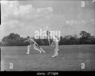 Match de Cricket- Couverture d'un match entre Kenton et Alexandra Park, Kenton, Middlesex, Angleterre, RU, 1945 Une scène pendant un match de cricket entre Kenton et Alexandra Park au sol. Kenton Le quilleur a juste fait une boule et un batteur commence à courir. Banque D'Images