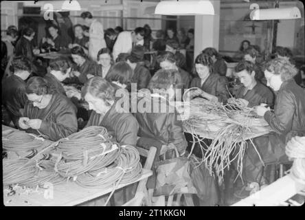 Fauteuils de bombardiers de la guerre- travailler à Perrings Exposition de meubles, à Kingston, Surrey, 1943 femmes à temps partiel Travailleurs guerre préparer les câbles électriques pour l'équipement des bombardiers dans une section de Perrings exposition de meubles à Kingston. Dans l'arrière-plan, les superviseurs (portant des manteaux blanc) peut être vu, en vous assurant que le travail est effectué correctement. Banque D'Images