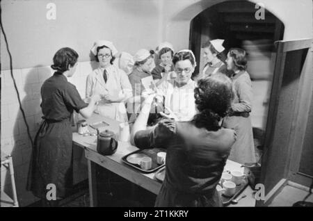 Guy's Hospital- La vie dans un hôpital de Londres, Angleterre, 1941 Un groupe d'infirmières et à Guy's Hospital à Londres get tasses de thé à partir de la cantine, versé pour acheter les membres de la Women's Voluntary Service (WVS). Il existe différents types d'infirmières au travail à Guy's, y compris VADs (détachement d'aide volontaire des infirmières) et ceux de la Croix-Rouge. Banque D'Images