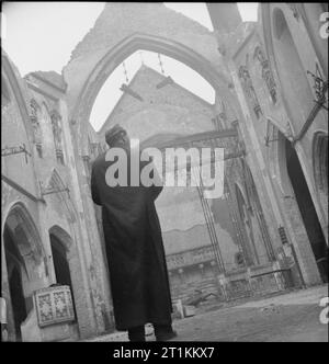 Une Église s'élève de ses cendres pour dommages causés par les bombes- St George's Cathedral, Southwark, 1942 Père Frederick Dixon les dommages relevés pendant qu'il regarde vers ce qui était autrefois l'autel de St George's cathédrale catholique romaine, à l'angle de St George's Road et Lambeth Road à Southwark, au sud-est de Londres. La Cathédrale est maintenant un shell sans toit, à la suite d'une attaque à la bombe incendiaire qui détruit le bâtiment le 16 avril 1941. Banque D'Images