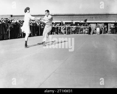 Camp de vacances commence encore une fois- la vie quotidienne dans un camp de vacances Butlin, Filey, Yorkshire, Angleterre, Royaume-Uni, 1945 Des Couples prendre un tour sur la patinoire à Butlin's Holiday Camp, Filey, comme la foule se tenir autour du bord au soleil, à regarder l'action. Banque D'Images