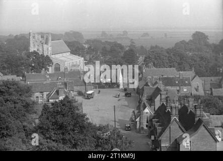 Village d'invasion- la vie quotidienne à Orford, Suffolk, Angleterre, 1941 une large vue sur le village d'Orford, prise depuis le sommet de la tour du château, montrant des maisons et des véhicules. Dominant l'horizon est la tour de l'église de Saint-barthélemy, visible sur la gauche de la photo, juste en face des champs et arbres en arrière-plan. Banque D'Images