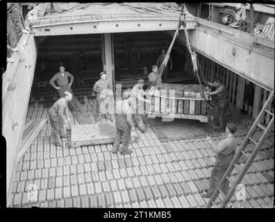 L'accumulation de l'invasion- Les préparatifs pour les débarquements du jour J, UK, 1944 bidons d'essence sont abaissées par grue dans la cale d'un navire à un port, quelque part en Grande-Bretagne, en préparation pour le transport vers le deuxième front. Banque D'Images