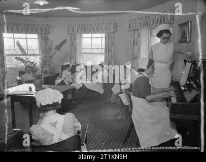 Hôtel particulier devient maison de maternité- La vie à Brocket Hall, Welwyn, Hertfordshire, 1942 infirmières lire ou jouer du piano comme ils vous détendre dans leur salle de séjour à la fin d'une journée bien remplie à Brocket Hall de l'hôpital de maternité. Banque D'Images