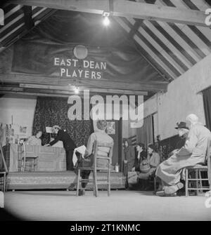 Mme clairon Goes To War- la vie quotidienne au doyen, Sussex, Angleterre, 1943, à la salle des fêtes au doyen, les villageois sont en mettant sur une représentation de la pièce "Trop de femmes'. Les acteurs sur la scène sont Ray Kemp et Mme Waffenden. Diriger le jeu est Mme Wynne, qu'on voit ici avec son dos à la caméra, regarder l'action. Plusieurs autres villageois, dont Mme clairon et Mme Russell, (qui a joué dans la pièce comme Mme Brown), peut être vu à regarder les répétitions. La compagnie de théâtre est connu sous le nom de "East Dean Players'. Banque D'Images