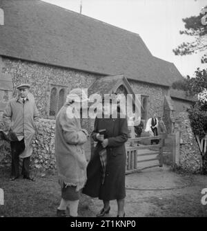 Mme clairon Goes To War- la vie quotidienne au doyen, Sussex, Angleterre, 1943 Mme clairon chats à un ami à l'extérieur de l'église de St Simon et St Jude, Doyen de l'Est, après le service du dimanche. Dans l'arrière-plan, le vicaire, le révérend W E N Williams, peut être vu parler à d'autres paroissiens. Mme clairon du défunt mari est enterré dans ce cimetière. Banque D'Images