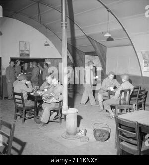 Les cantines Naafi accueillir des troupes US- les travaux de la Marine, l'armée et la Force aérienne Instituts, Angleterre, RU, 1943 les troupes américaines se détendre à un, NAAFI quelque part en Angleterre. Les hommes profitent de tasses de thé et café, d'autres sont la lecture de revues et journaux. Le poêle peut être vu dans le milieu de la chambre et le soldat qui traversent la salle après la collecte d'une tasse de thé est le Caporal George F Scruggs de 11040 Vernon Sud Avenue, Chicago, Illinois. Banque D'Images