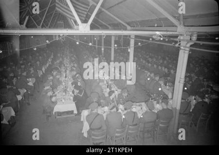 Les Forces alliées célébrer Pâque- traditions juives en temps de guerre La Grande-Bretagne, avril 1944 Service technique siéger à de longues tables à tréteaux pour profiter de leur repas de Pâque dans une grande salle, quelque part près de Londres. Les hommes et les femmes de toutes les branches des forces armées et de nombreux pays différents sont clairement visibles. Haut au-dessus de leurs têtes dans les poutres de la salle, les drapeaux de l'Amérique et le Royaume-Uni peut être clairement vu. Banque D'Images